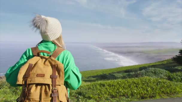 身披燕尾服 头戴燕尾服 身穿浅绿色毛衣 背负盈亏的金发美女形象 尽享美丽的海洋景致 美国北卡罗来纳州的自然探险 — 图库视频影像