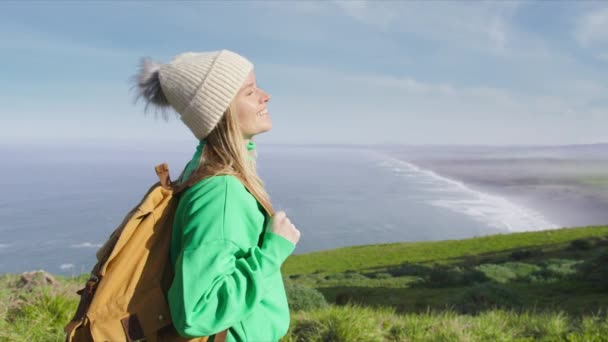 明るい太陽とスクイントを見て幸せな笑顔の女性のサイドビューの肖像画 緑の丘からの美しい海の景色を楽しみながら 手の手のひらで観光客が目を閉じます 自然の冒険 California Usa — ストック動画