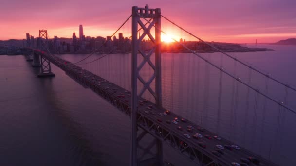 从空中俯瞰驾驶者和乘客在海湾大桥上的交通情况 可以看到壮观的玫瑰色金色落日和旧金山市在海滨和史诗般的红色黄日的轮廓 — 图库视频影像