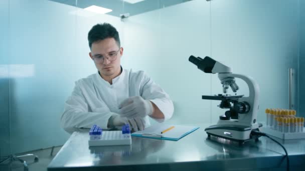 由医学研究科学家进行的Dna测试实验 使用试管和显微镜 并在生物科学实验室写下报告分析 专业实验室4K的白衣工程师 — 图库视频影像