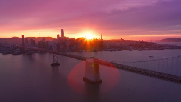 引人注目的粉色金色落日云彩笼罩在旧金山五彩斑斓的落日天空之上 金融区大楼和湾桥 旧金山市市中心 在史诗般的玫瑰紫色落日的天空4K空中 — 图库视频影像