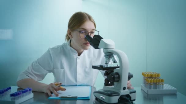 遺伝子治療やウイルスワクチンの顕微鏡検査に取り組む女性生化学者 医療科学研究所4Kのスローモーション バイオテクノロジーの専門家女性科学者 — ストック動画