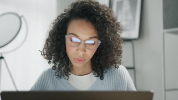 遠隔大学のウェビナーに出席眼鏡の集中大学生 仮想教室の家を持っています ラップトップコンピュータを使用して巻き毛を持つ集中した女の子遠隔オンラインセミナークラスを見て — ストック動画