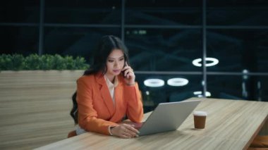 Pozitif melez iş kadını iş yerinde ağır çekimde telefonla konuşuyor. Portre işindeki kadın ev içinde 4K 'yi arıyor. Güzel Asyalı kadın konuşan cep telefonu gece yarısı ofiste.