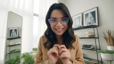 Sevimli, komik, serbest girişimci video görüntülü arama kamerasında kendini beğenmiş biriyle dalga geçiyor. Gözlüklü, gülen Latin bir kadın dokunaklı parmaklarını kameraya yaklaştırıyor.