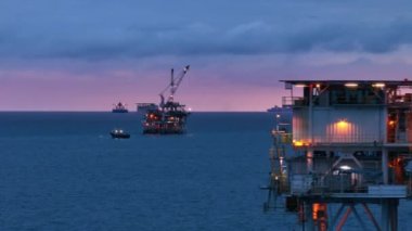 Mavna, San Pedro Kanalı, ABD 'de bulunan sondaj kulesine doğru yüzüyor. Açık deniz teçhizatı, gemiler akşam saatlerinde çalışmaya devam ediyor. Yüksek kalite 4k görüntü