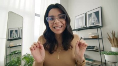 Webcam view tapılası komik serbest girişimci aptal suratlar ve el hareketleriyle 4K üzerinde çalışıyor. Süper tatlı, heyecanlı, gözlüklü İspanyol kadın konferans videosuyla kameraya konuşuyor.