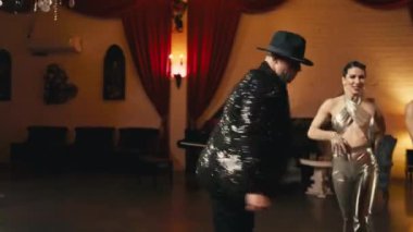 Modern funk caz koreografisinin elementleri genç dansçı çiftler tarafından klas retro stüdyo arka planında sahneleniyor. Erkekler ve kadınlar tutkulu bir şekilde dans ediyor, duygularını yavaş çekimde ifade ediyorlar.