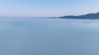 İnsansız hava aracı, ufuktan ufka kadar sonsuz bulut denizinin üzerinde hızla uçuyor. İnanılmaz doğa manzarası, gökyüzünde 4K drone. Yoğun sisli bulutların üzerinde dron yükseliyor. Güneş doğarken pembe gökyüzü ile mavi bulutlardan oluşan güzel bir okyanus.