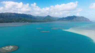 Kaneohe Körfezi 'nin üzerindeki temiz mavi suları ve arka planında yeşil orman dağları olan manzaralı kumsallar. Oahu Adası, Hawaii 4K ABD Turizmi 'nde yaz tatili