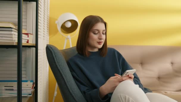 Smiling Pretty Young Brunette Browsing Smartphone Sitting Comfortably Armchair Cozy — Stock Video
