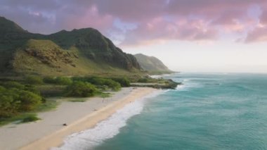 Günbatımında Makua plajı, Oahu. İnsansız hava aracı okyanus sahilinin üzerinde uçuyor. Yeşil volkanik dağlarda, dramatik okyanus kıyısının üzerindeki hava. İyi yaz tatilleri. Hawaii 'yi keşfeden turist adayı