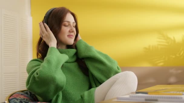 Красива Брюнетка Сидить Столом Кімнаті Чорних Навушниках Слухаючи Музику Жінка — стокове відео