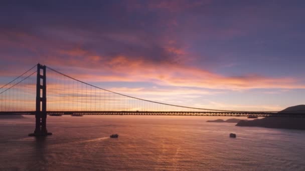 在世界著名的金门大桥轮廓的背景上 令人叹为观止的日落天空全景和粉色紫色的云彩 空中悬索桥旧金山地标在电影落日4K美国 — 图库视频影像