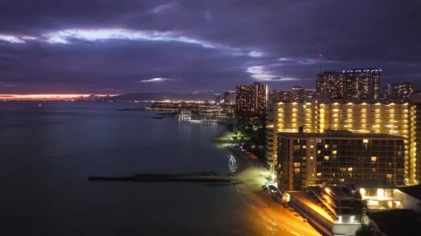 夕暮れ時の海岸ベイシティの美しい都市景観 ハワイ島の街のライト4K 日没後にダウンタウンワイキキビーチ 風光明媚なホノルルスカイラインパノラマ 夜のシーンでのオアフ島の空の景色 — ストック動画