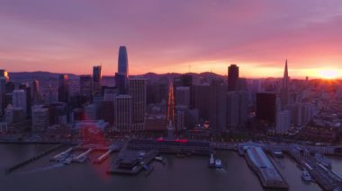 San Fransisco şehrinin deniz kıyısındaki binalar ve feribot terminali ve gece feribotları ile havadan insansız hava aracı görüntüsü. Dramatik günbatımında muhteşem bir ufuk çizgisi, California USA 4K 