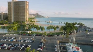 Wakaki plaj bölgesindeki Kahanamoku Sahili 'nin manzaralı mavi gölünde rahatlayan insanların sinematik Diamond Head arka planına sahip görüntüsü. Su, modern Waikiki tatil köyünde. Hawaii 'nin kurulması