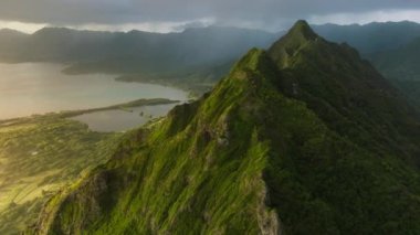 Volkanik dağların güzel sırtlarıyla manzaralı Oahu kıyıları. Okyanus kıyısındaki yeşil ve garip şekilli tepelerin inanılmaz manzarası. Kualoa Çiftliği 4K. Sinematik Hawaii Doğa manzaraları altın gün doğumunda