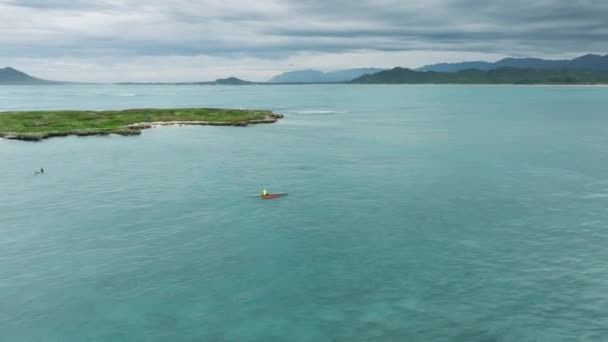 週末に屋外の水活動 カイルア湾の美しいティールブルーの海でポピア島でウォータースポーツを楽しむ人々 緑豊かなハワイの山々を背景に美しいカイルア村 — ストック動画