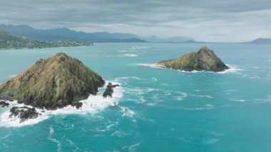 Manzaralı tropik ada manzarası. Pasifik Okyanusu 'ndaki adanın etrafındaki güzel mavi deniz mavisi sular. Hawaii turizm konsepti, Kailua arka planda. Bulutlu bir yaz gününde Na Mokulua adasının üzerinde uçan insansız hava aracı
