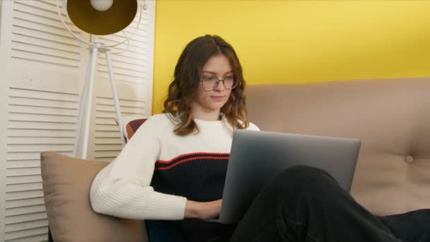 Mulher Nova Bonito Óculos Sentados Sofá Com Laptop Suas Pernas — Vídeo de Stock