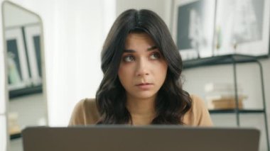 4K Slowmo apartmanında uzaktan not defterine yazan odaklanmış karışık ırk girişimcisi. Ev ofisinde oturan dizüstü bilgisayar kullanan Latin kız öğrencinin portresi.