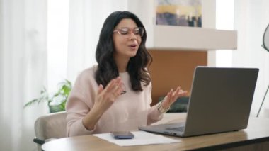 Bilgisayarda duygusal kadın portresi. Proje el hareketlerini uzaktan açıklayan profesyonel bir Latin. Gözlüklü zeki İspanyol iş kadını evdeki video konferansında konuşuyor.