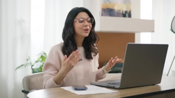 ビデオの感情的な女性の肖像は ラップトップコンピュータを呼び出します 専門家ラティーナは リモートでプロジェクトの手ジェスチャーを説明する スマートヒスパニックビジネス女性でアイウェアは自宅でビデオ会議で話す — ストック動画