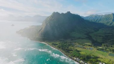 Yeşil dağ sırtı manzaralı maceralı arka plan. Dünyaca ünlü çekim yeri Kualoa Çiftliği 'nin gündoğumunun sinematik manzarası. Hawaii 'deki Oahu Adası' nda Jurasik dünyaya dokunulmamış.