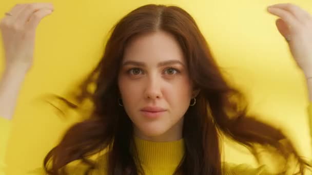 中等比例的小可爱 绿色的眼睛 冷酷的妆容 漂亮的发型 黄色背景的黄色毛衣 抚摸着她的头发 高质量的4K镜头 — 图库视频影像