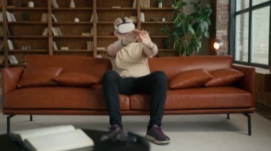 VR sanal gerçeklik internet konsepti. Sarışın hippi 3 boyutlu siber uzay için kulaklık kullanıyor. Genç adam web sitelerine göz atıyor, sayfaları yana kaydırıyor, video yayın hizmetlerini izliyor, Sosyal Medya 4K kullanıyor