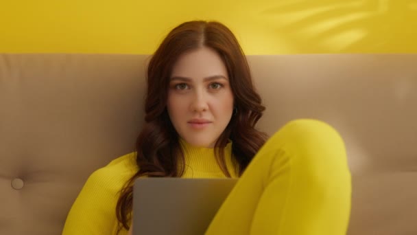 Sarı Elbiseli Kanepeye Oturmuş Dizüstü Bilgisayarda Yazı Yazan Kameraya Bakışlar — Stok video
