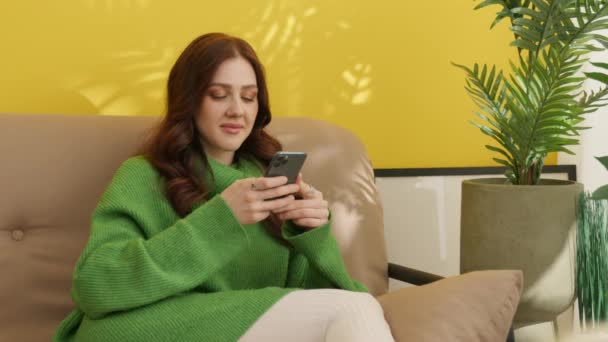 Sorrindo Muito Morena Navegando Telefone Celular Sentado Sofá Com Pernas — Vídeo de Stock
