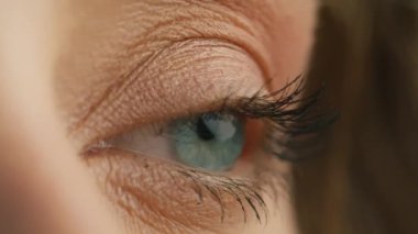 Side view macro close up of light blue female eye opening. Fashion model, natural day makeup mascara on eyelashes. Blue iris natural beauty looking aside. Opening and closing blue eyes beautiful girl