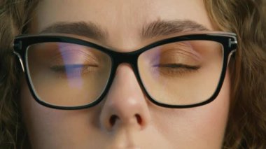 Close up view of focused businesswoman wears stylish computer glasses for reducing eye strain blurred vision looking at camera. Smart people healthy vision concept. Beautiful woman with blue eyes 4K