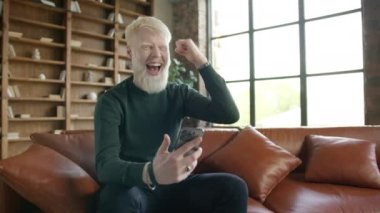 Albino amazed businessman receiving sms message offer opportunity. Super excited happy man reading good news on smartphone. Overjoyed caucasian male winner celebrating success mobile phone victory 4K
