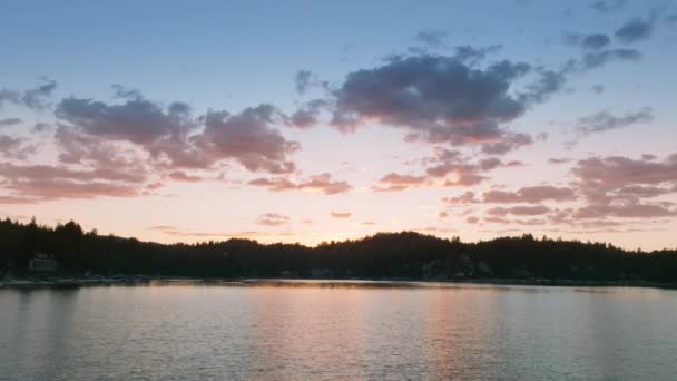 サンバーナーディーノ山脈 ロサンゼルス カリフォルニア アメリカのアローヘッド湖のウォーターフロント上を飛行するドローン 穏やかな水面を反映した日没の光線 夜空のカラフルな雲 4K映像 — ストック動画