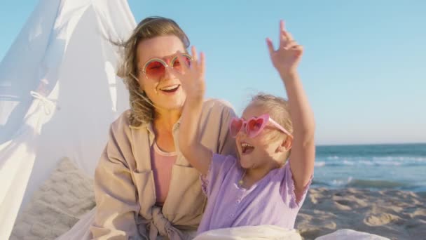 在金光闪闪的阳光下 快乐的爱之家的画像 女人为孩子创造快乐的回忆 快乐的孩子在母亲的身边玩耍 年轻快乐的女人和女儿一起在电影 日落海滩 中大笑 — 图库视频影像