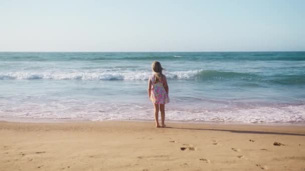 夏の暖かい晴れた日に海の海岸で遊んでいる女の子の子供 コピーバックでスローモーションで夏休みのコンセプト 幸せな家族 夢の子供のコンセプト4K 子供女の子楽しんでいますで砂浜 — ストック動画