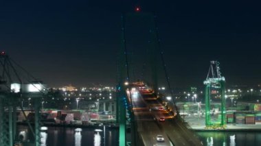 İHA, San Pedro şehir limanı üzerindeki asma köprü üzerinde uçuyor. Los Angeles Limanı, batı kıyısı, Kaliforniya, ABD. Gece aydınlık köprüde arabalar hareket ediyor. Yoğun Uluslararası Liman