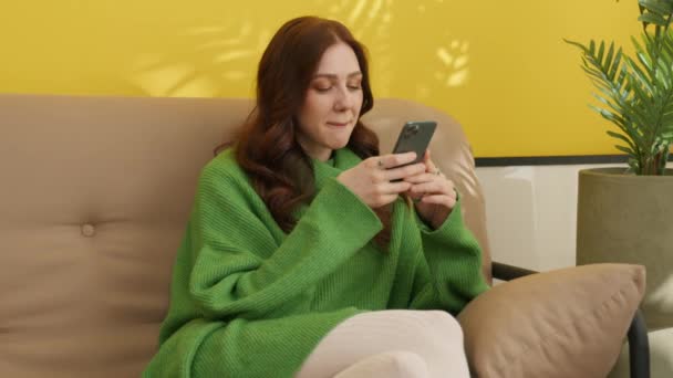 Akıllı Telefonuyla Koltukta Oturan Mutlu Kız Cep Telefonunda Mesaj Yazan — Stok video
