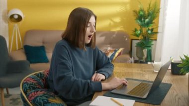 Mutlu kadın evde iyi haberi kutluyor. Laptop kullanan duygusal kız. Bilgisayar klavyesinde daktilo eden kız öğrenci. Kapalı alanda zaferin tadını çıkaran pozitif kadın. Genç model cevap e-postası, 4k görüntü