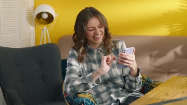 Positiv Pige Griner Med Smartphone Hånden Glædelig Studerende Hviler Derhjemme – Stock-video