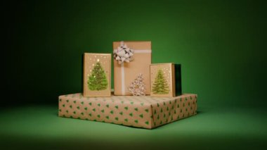 Sihirli Noel arifesi için sürpriz hediyeler, yeni yıl partisi. Mutlu 2024 Yeni Yıl zarif ve basit bir kavram geçmişi. Koyu arka planda izole edilmiş yeşil Noel ağacı desenli hediye kutuları.