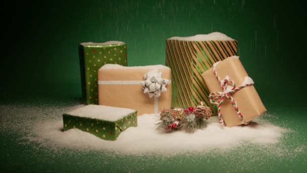緑の背景に隔離されたクリスマスの装飾とクラフト紙の光沢のある緑のギフト用の箱の積み重ねに落ちる雪 クリスマスのサプライズプレゼント ハッピー2024 新年のプレゼントバックグラウンド4K人形 — ストック動画