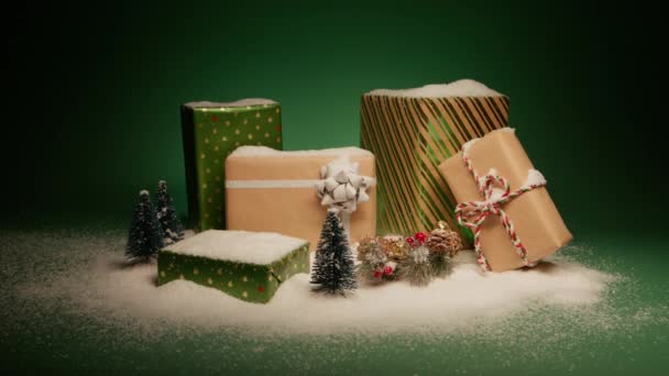 冬季仙境展现了概念 雪堆在闪闪发亮的绿色和手工礼品盒与松树装饰隔离在绿色背景 圣诞前夜的惊喜礼物新年快乐 — 图库视频影像