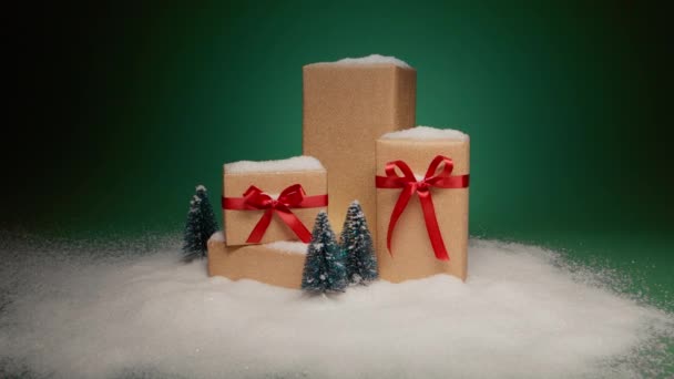 クリスマスイブのサプライズギフト ドリーは エレガントなサテン赤い弓と松の木が緑の背景に描かれた黄金のギフトボックスのスタックに赤いカメラの雪だるまを撮影しました ウィンターワンダーランドが4Kをプレゼント — ストック動画