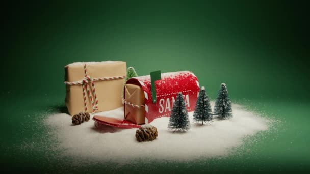 雪の下にクリスマスの装飾とオープンレッドメールボックスでサンタクロースのプレゼント ドリーは緑色の背景に描かれた紙の箱の赤いカメラを撮影した ウィンターワンダーランド 願いのクリスマスコンセプトを作る — ストック動画