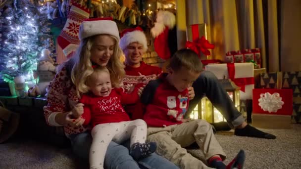 Lycklig Familj Samlades Julafton Nära Julgranen Unga Vackra Föräldrar Röda — Stockvideo