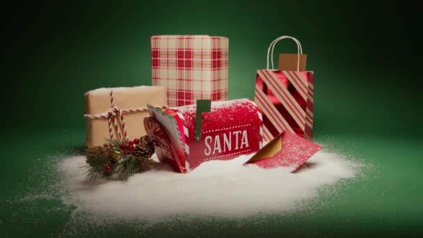 願い事 クリスマスの背景 冬のワンダーランド4Kを作る サンタ村の贈り物と赤いメールボックスを開いた子供からの手紙 クリスマスの装飾 緑の背景に白い雪で覆われたギフト用の箱 — ストック動画